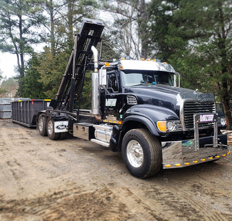 A black roll-off truck with the Value Waste logo parked near a residential driveway.
