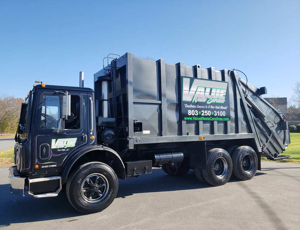 A black garbage truck with the Value Waste logo, parked on a street.
