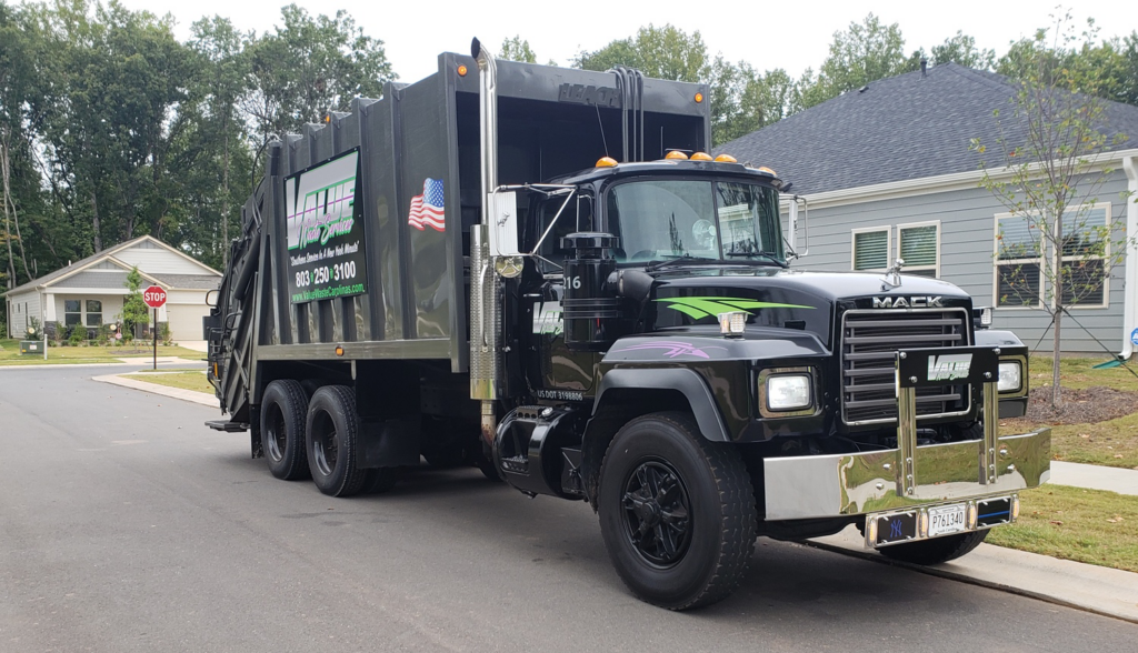 A black garbage truck with the Value Waste logo, parked on a residential street.