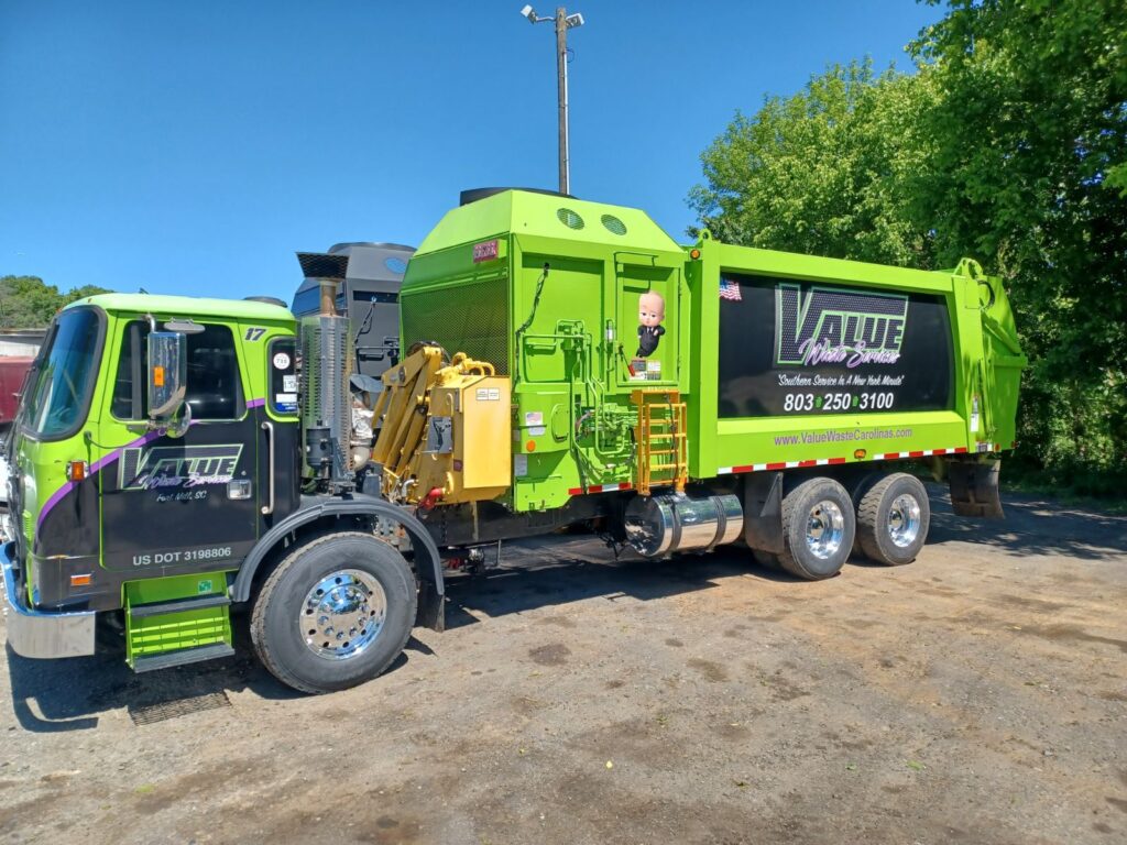 A green garbage truck with the Value Waste logo parked on a street.